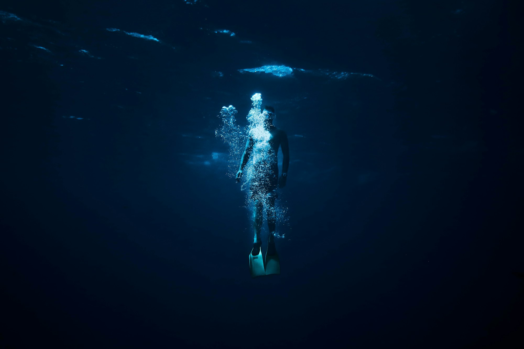 A lone diver descending into deep blue water